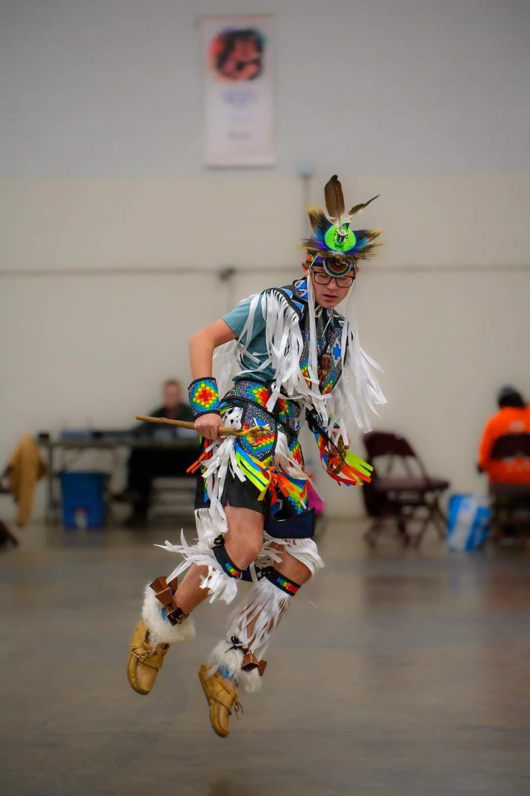 Photo of committee member wearing indigenous ceremonial clothing and dancing
